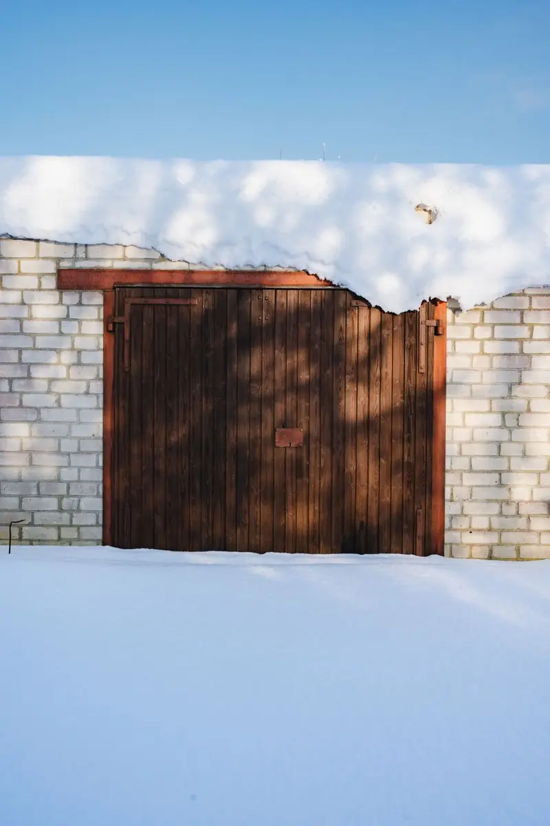 Wooden garage door under snow in a Fall River, MA winter — the season when springs snap